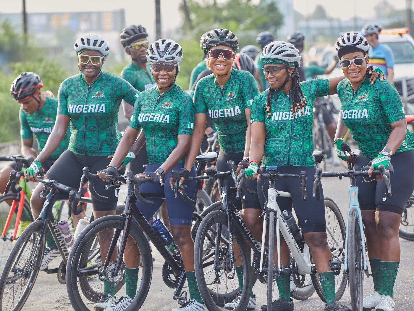 Cycology riders in Nigeria kit, all wearing helmets, paused together beside their bikes